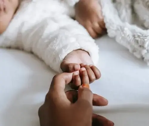 Baby and parent holding hands